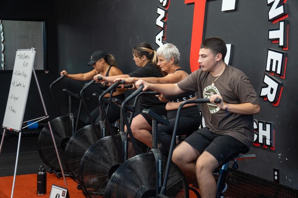 Members of a range of ages working out on air bikes.